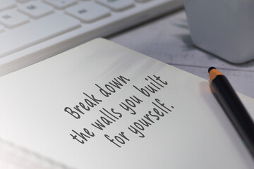 Motivational quote on notepad - Break down the walls you built for yourself.
