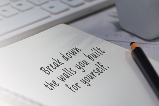 Motivational quote on notepad - Break down the walls you built for yourself.