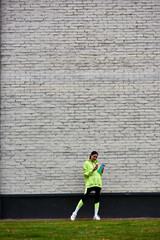happy sportswoman in hoodie and leggings using smartphone and standing with bottle with water