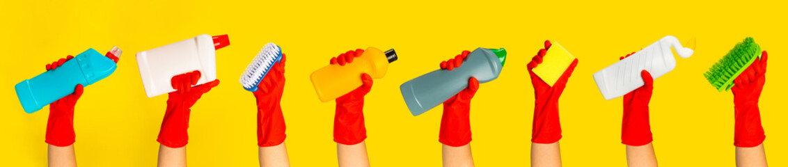 Hand with a red rubber glove holding cleaning products on a yellow background. banner. Cleaning...