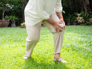 Senior woman suffering with knee pain during walk in garden.