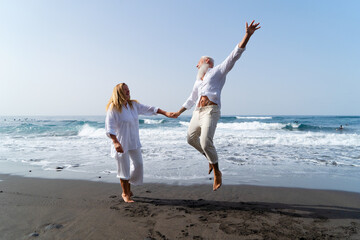 lifestyle with caucasian senior couple jump fun on beach, happy in love romantic and relax time,...