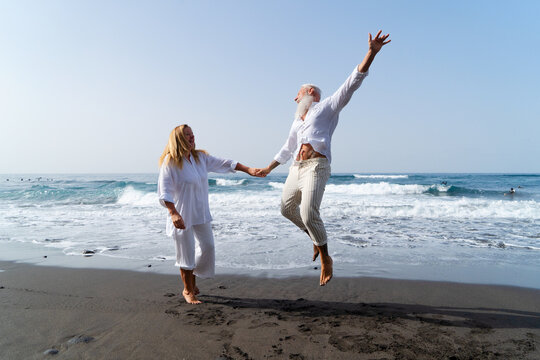 lifestyle with caucasian senior couple jump fun on beach, happy in love romantic and relax time, tourism of elderly family pleople, leisure and activity travel after retirement in vacations and summer