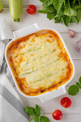 Delicious zucchini lasagna with sauce bolognese in a baking dish on a white wooden bachground. Healthy food. Top view. Selective focus.
