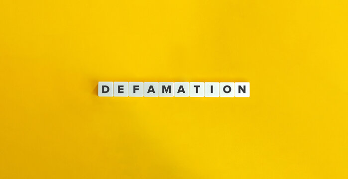 Defamation Word on Letter Tiles on Yellow Background. 