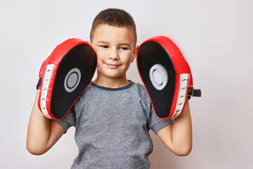 Little cheerful boy put on boxing paws on his hands.