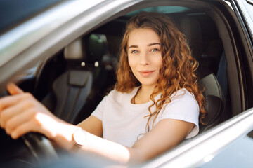Portrait of a beautiful young woman driving a car. Happy woman traveling by car in casual clothes....