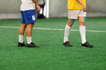 Fototapeta premium Futsal five-a-side players on artificial grass field indoor.