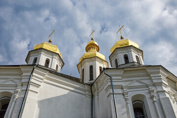 The Catherine's Church, a stunning white church with regal golden domes, as it rises majestically against the backdrop of a tranquil blue sky with soft, billowing clouds.