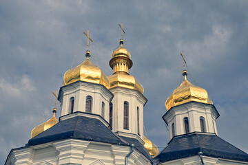 Fototapeta na wymiar The golden domes of a Orthodox Church, standing majestically against a backdrop of a clear blue sky. Gilded domes of an ancient Orthodox church against the sky.
