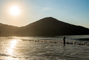 Homem se prepara para nadar no oceano durante o nascer do sol