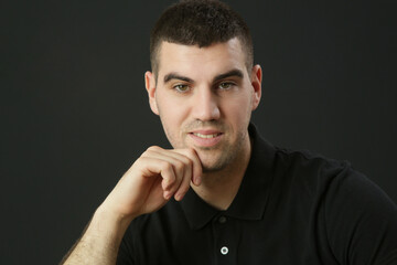 Studio portrait of young man in black polo shirt on the black background