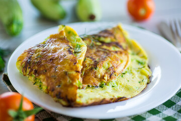Fried omelet with zucchini, on a wooden table.