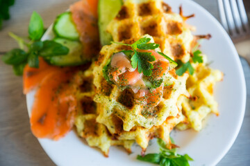 Cooked potato waffles with lightly salted red fish and herbs in a plate.