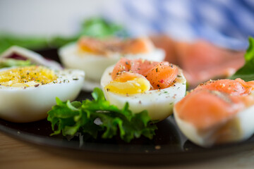 boiled eggs with salted red fish, herbs and seasonings in a plate .