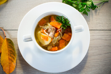 Autumn soup with chicken, noodles and autumn vegetables in a bowl .