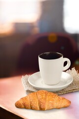 Breakfast of croissant and coffee cup in cafe background.