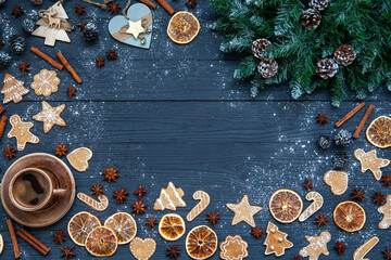 Christmas background, holiday mood. Fir branches with cones, a cup of coffee, gingerbread cookies, star anise, cinnamon, Christmas decor on a dark wooden table background with copy space.
