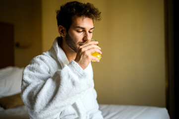 A man in a white robe drinking orange juice