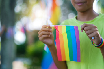 Celebrating LGBTQ pride month with flag closeup, young asian kid happy smiling with nature...