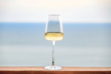 White wine in glass against a background of blue sky and sea. Front view. Copy Space.