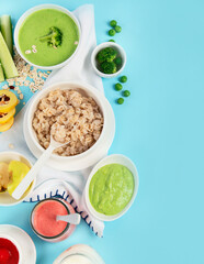 Bowls with healthy baby food on blue background.