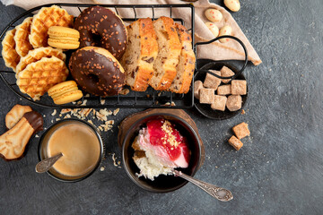 White coffee with delicious cookie, donuts, cake, sugar, waffles. Hot drink with sweets on dark background.