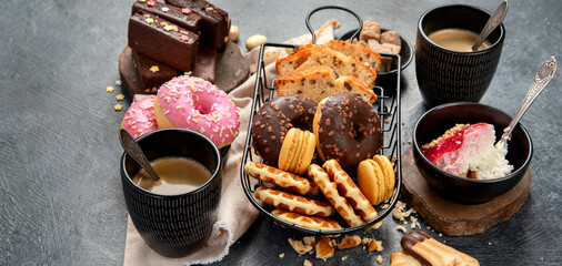 White coffee with delicious cookie, donuts, cake, sugar, waffles. Hot drink with sweets on dark background.