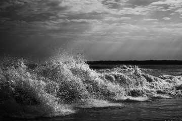 Beachscape with radiant sun rays breaking through the clouds and waves crashing