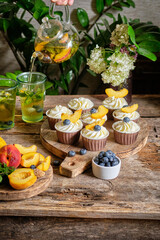 Peach mint tea and blueberry and peach cupcakes. Side view, wooden background.