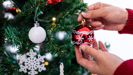 Merry christmas and happy holidays, hand of a woman is decorating the tree. Xmas