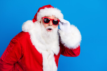 Photo portrait of pensioner senior man touch glasses astonished dressed stylish santa claus costume coat isolated on blue color background