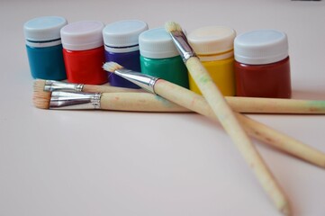 Jars with bright gouache paints and artistic bristle brushes of different sizes. Materials for...