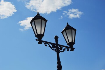 Fototapeta na wymiar Black street glass lanterns against a blue sky. City lighting.