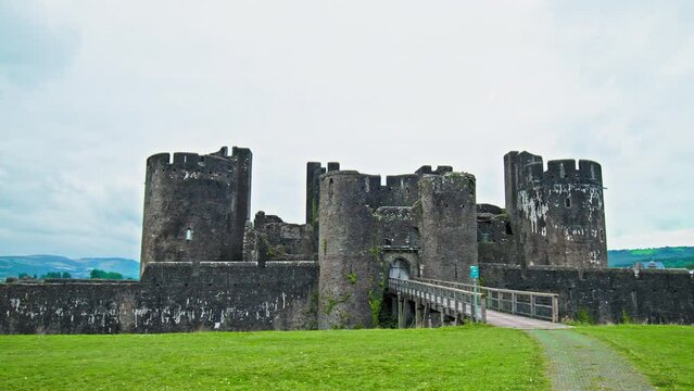 Caerphilly Castle in Wales. Moated fortress with an imposing gatehouse, a fortified dam and a tower.