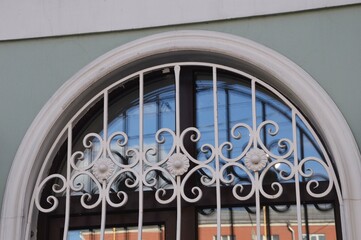 A window with an arch and an openwork white lattice on the wall of a building. Facade element.