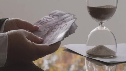 closeup female hands count paper 500 euro banknotes of eu against background of scattered paper banknotes on table, hourglass, concept Time is money, money laundering, financial scam - Powered by Adobe