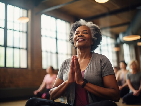 Smiling senior black woman doing yoga at gym