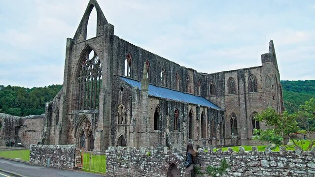 A beautiful woman visits the ruins of the National Icon Monastery of Tintern Abbey in Wales. Ruins of a Cistercian abbey with Gothic West Front in the village of Tintern in Monmouthshire, Wales
