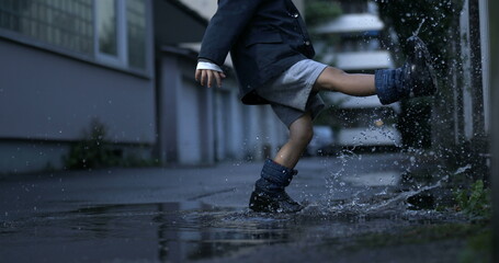 Child kicking puddle of water with rainboots creating splash captured in super slow-motion at 800...