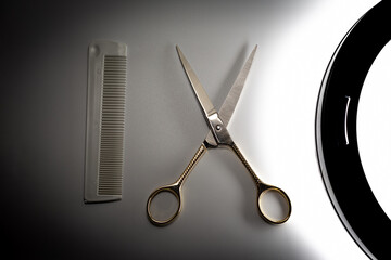 Golden scissors and plastic comb under makeup light on white background. Beauty, fashion, haircut,...