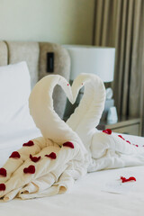 Fototapeta na wymiar Sweet room in holiday, Swan towel decoration on bed with white pillow in bedroom interior.