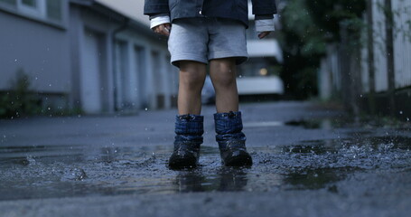 Child jumping in the air and splashing into water puddle captured in 800 fps with a high-speed...