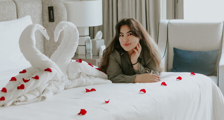 Portrait of the woman with Swan towel decoration on bed with white pillow in bedroom interior © tashmetova808