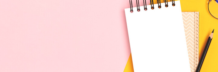 Banner with clean notepad mockup, eyeglasses and stationery on a pink and yellow background. - obrazy, fototapety, plakaty