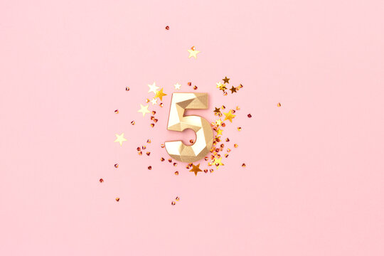 Golden number five and stars confetti on a pink background. Festive creative concept.