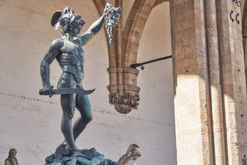 Bronze statue of Perseus with the head of Medusa, masterpiece by Benvenuto Cellini in Florence, Loggia dei Lanzi in the background in Florence - obrazy, fototapety, plakaty