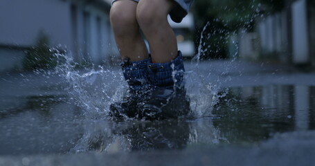 Joyful Splash - Kid in Rainboots Reveling in the Delight of Jumping into Puddles, Captured in...