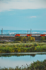 Passenger Train on countryside landscape in between colorful autumn trees in forest, Volga river Russia, Saratov