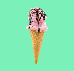 A wafer cone with strawberry ice cream and chocolate syrup with a green background 